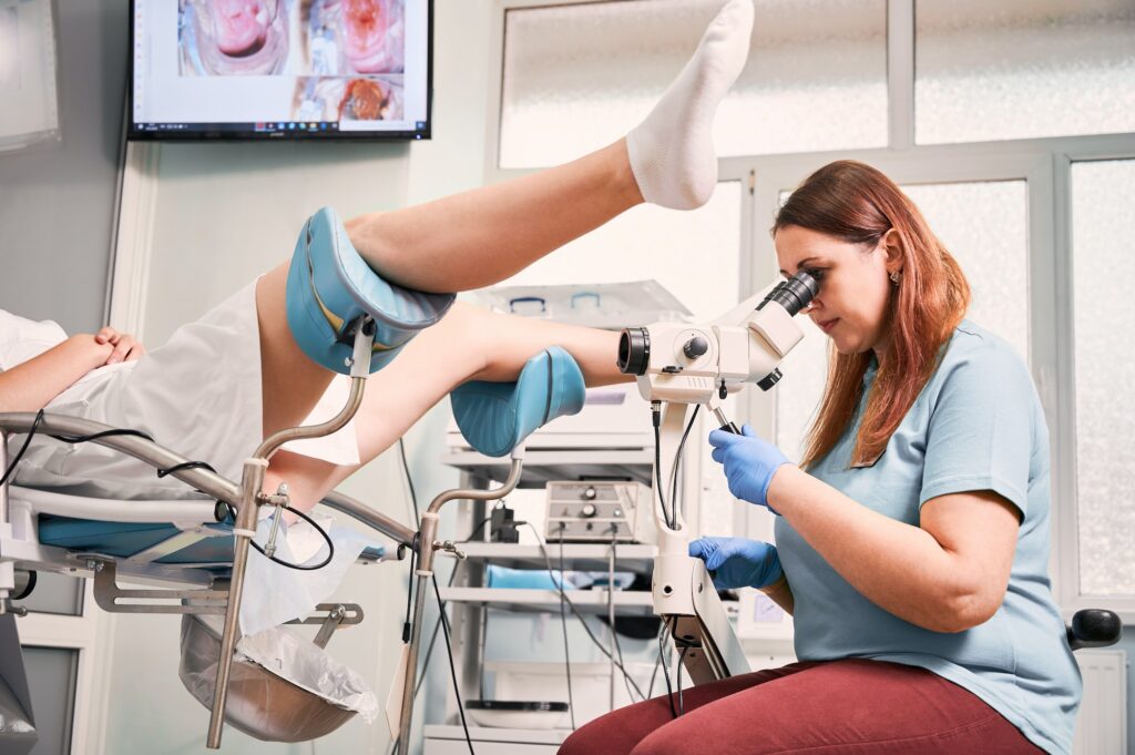 Gynecologist examining female patient with colposcope.